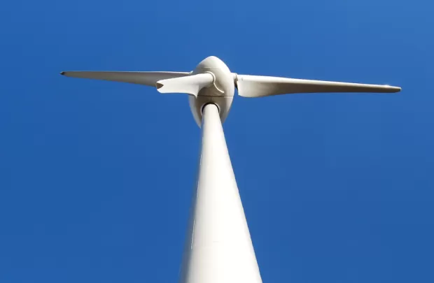 A wind turbine with as blue sky in the background - Scotland’s Our Power campaign urges Holyrood parties to ensure communities benefit from the renewable energy boom through public investment, jobs, and local ownership.